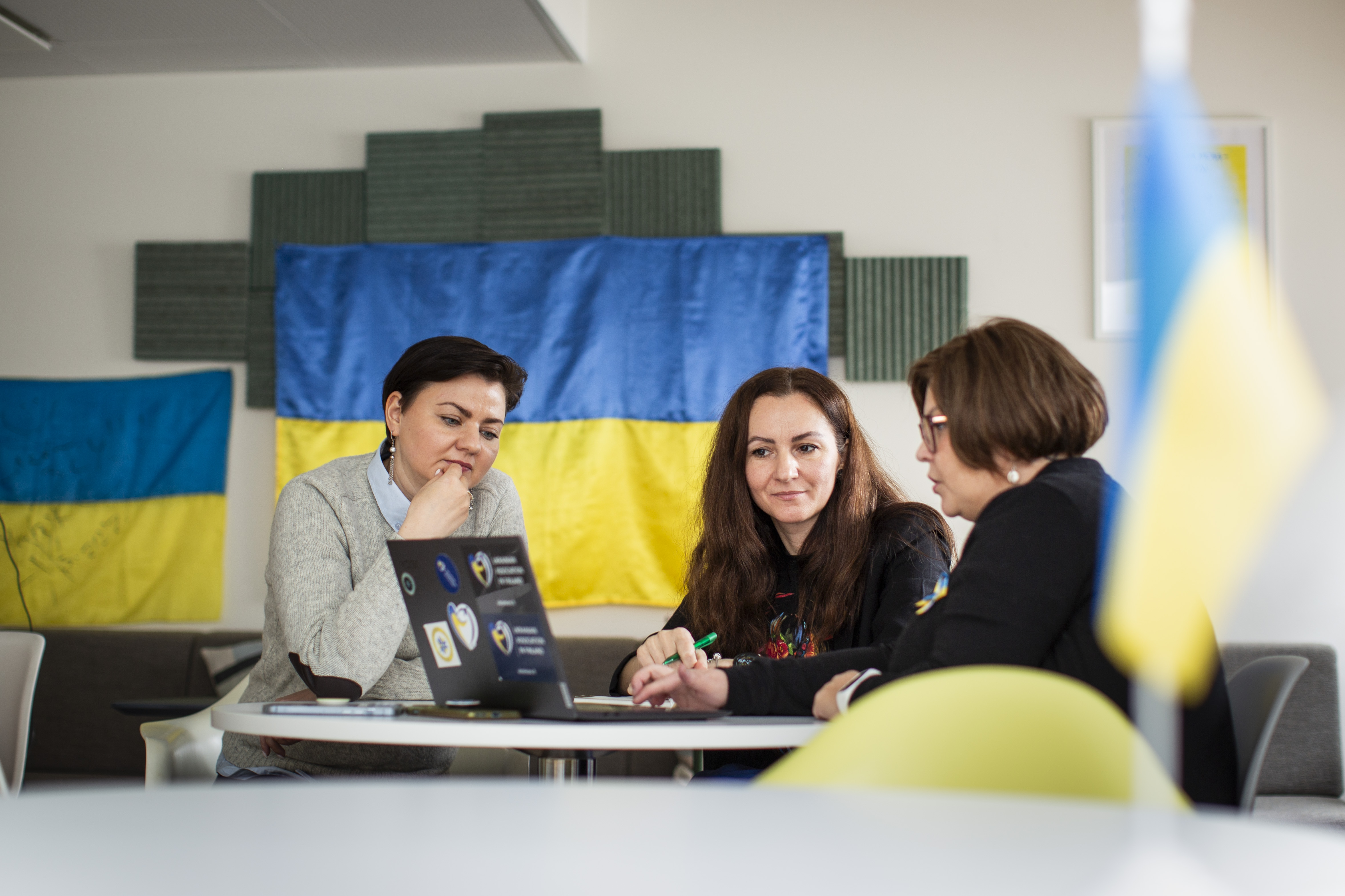 Kuvassa Viktoriia Konontšuk, Nadiya Maksymyuk ja Olena Skorokhod keskustelevat pöydän ääressä.