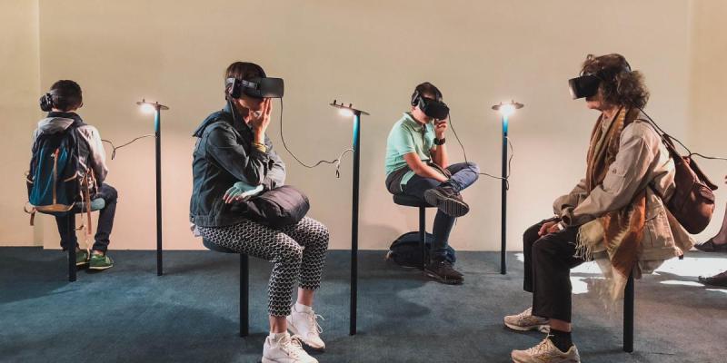 Kuvituskuva. Pohtivan näköisiä ihmisiä istuu tuoleilla VR-lasit päässään.