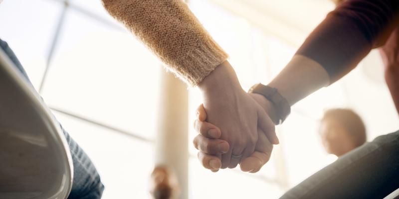 Kuvituskuva, jossa ihmiset pitävät toisiaan kädestä kiinni aurinkoisessa huoneessa.